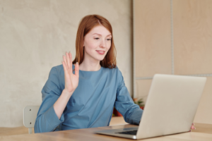 woman holding up her hand in front of a laptop