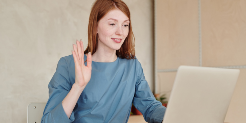 woman holding up her hand in front of a laptop