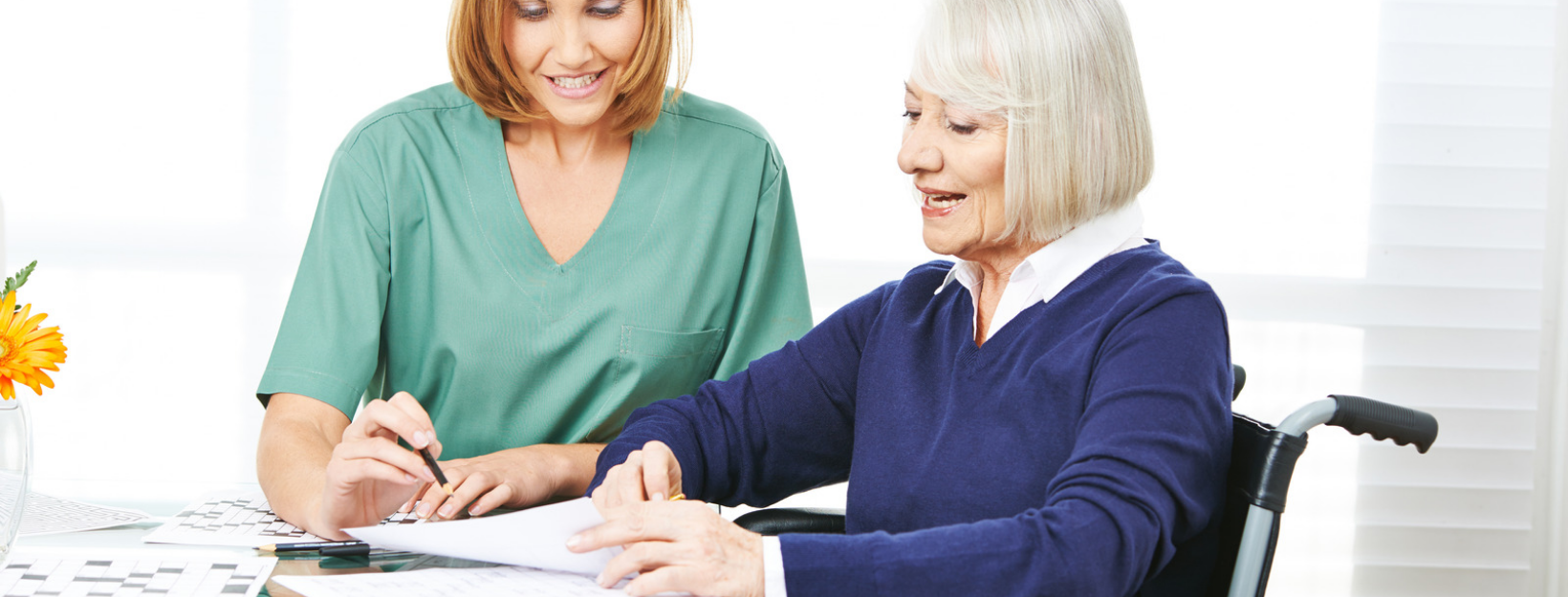 caregiver helping eldrly woman fill out forms