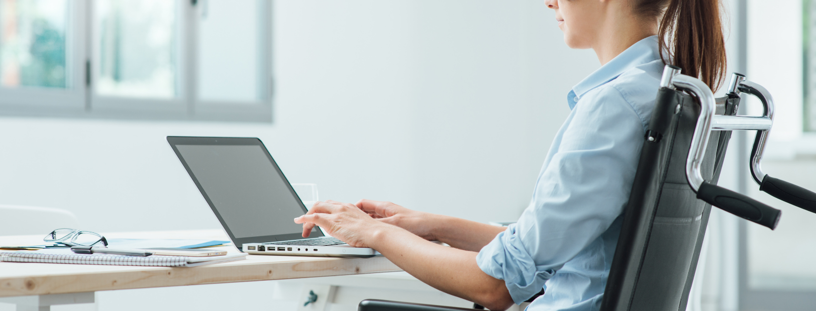 woman in manual char working in front of laptop