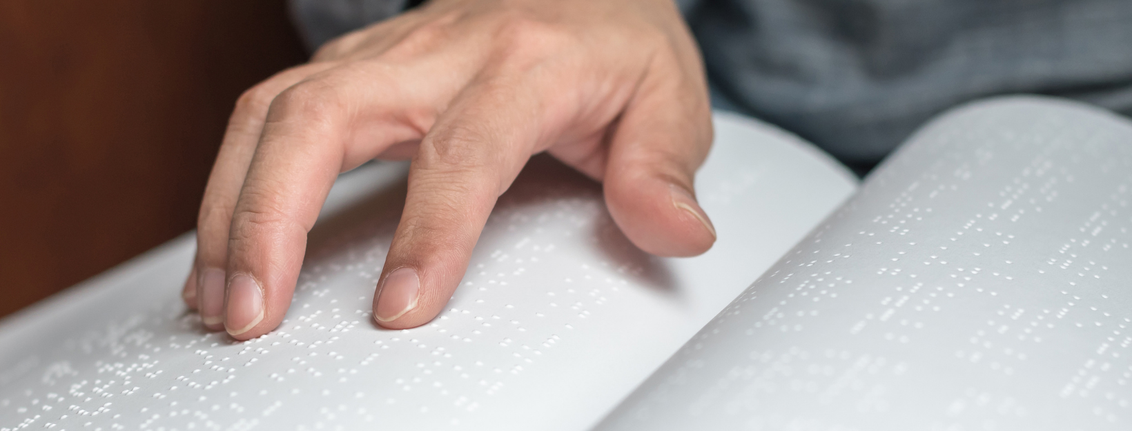 close up of a white man's fingers reading book in Braille